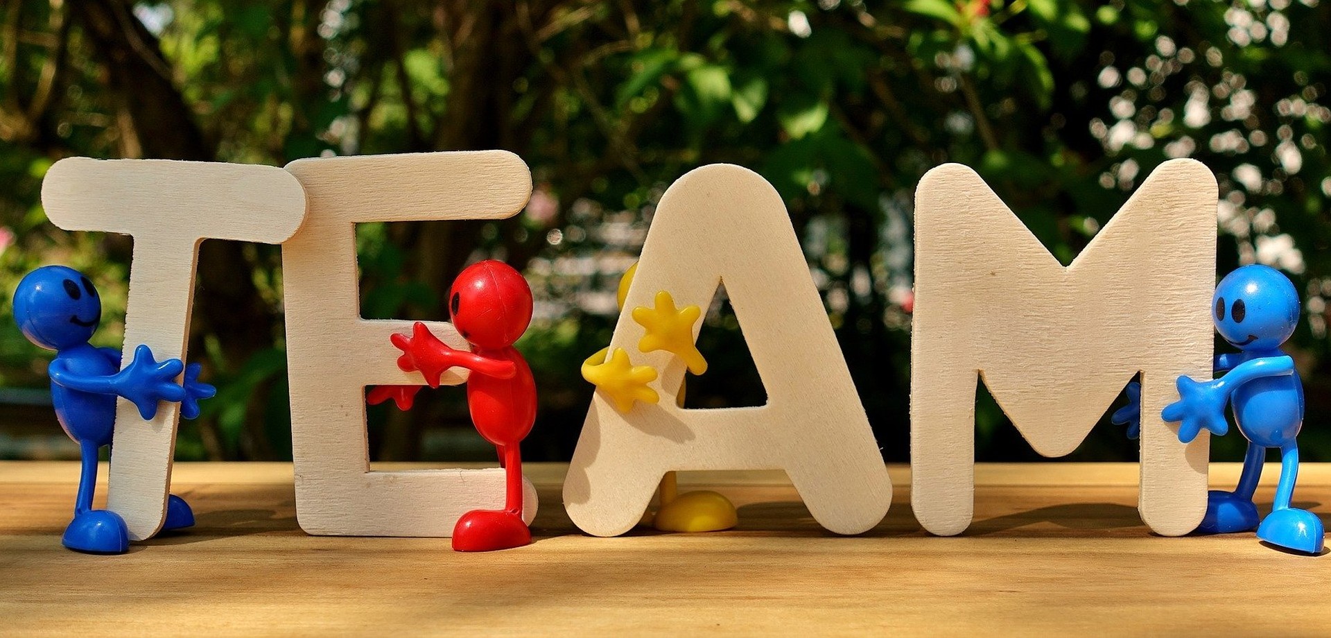 Bunte Plastikfiguren halten die Buchstaben des Wortes TEAM. Bild: pixabay